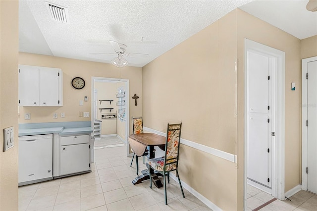 kitchen featuring light tile patterned flooring, dishwasher, a textured ceiling, ceiling fan, and white cabinets