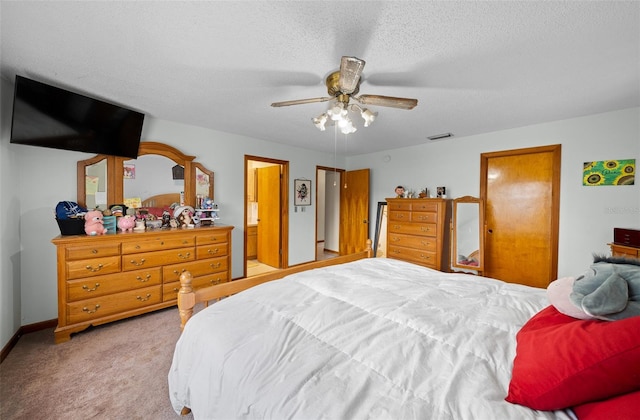 bedroom with ensuite bath, a textured ceiling, light colored carpet, and ceiling fan