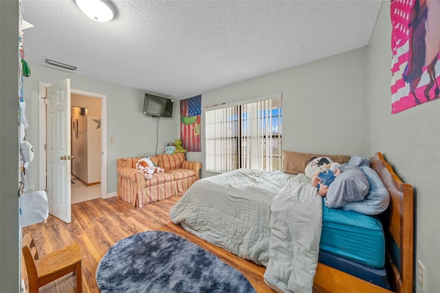 bedroom with a textured ceiling and wood-type flooring