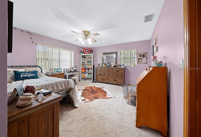 bedroom featuring a textured ceiling, light colored carpet, and ceiling fan