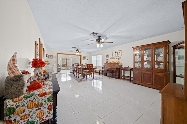 dining area with a textured ceiling, ceiling fan, and light tile patterned floors