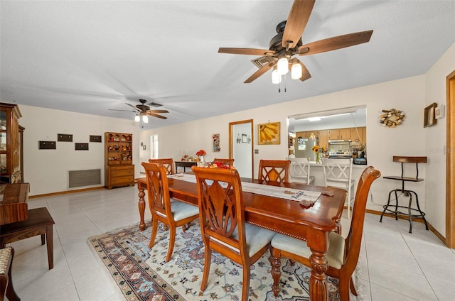 tiled dining area featuring ceiling fan and a textured ceiling