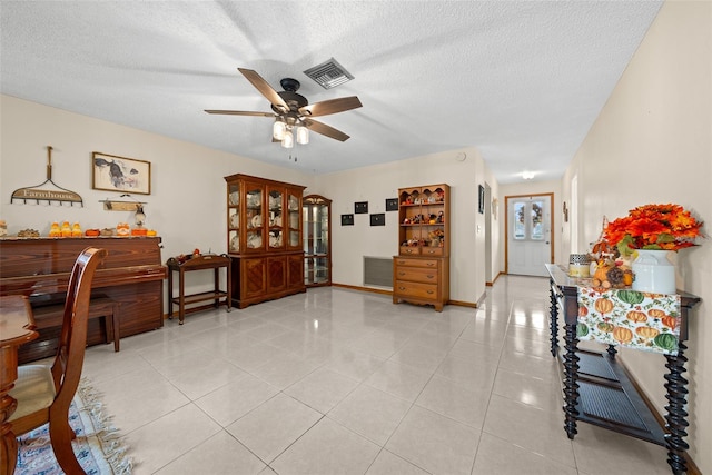 interior space with ceiling fan, a textured ceiling, and light tile patterned floors