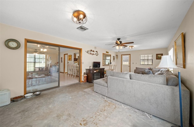 living room with ceiling fan, a textured ceiling, and concrete floors