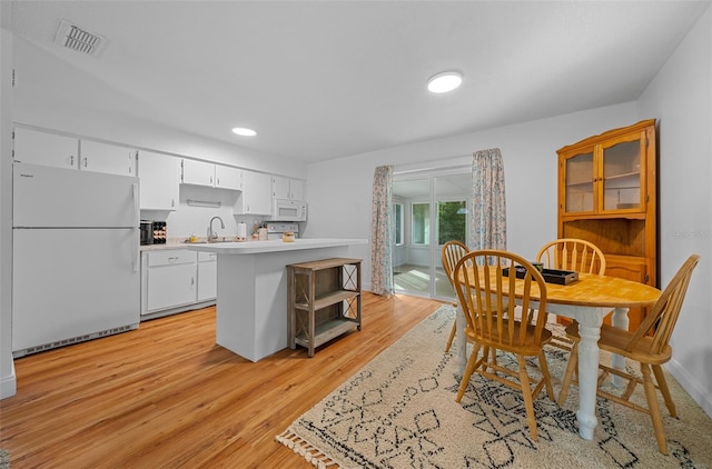 kitchen with sink, white cabinets, light hardwood / wood-style flooring, and white appliances