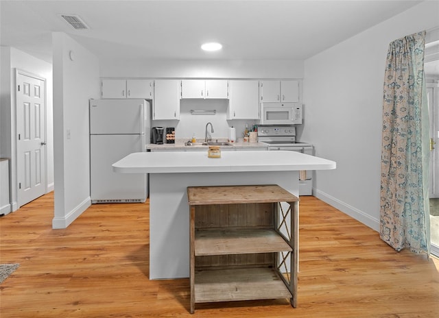 kitchen featuring white appliances, white cabinetry, light wood-type flooring, and a kitchen island