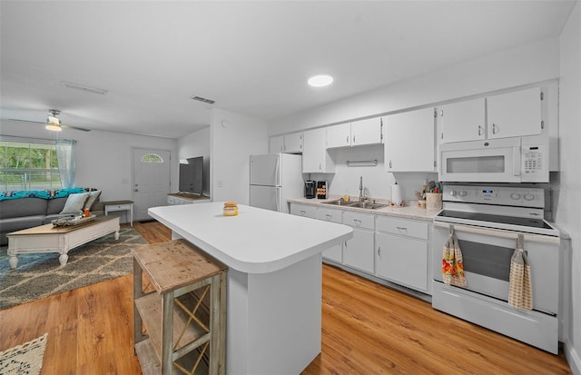 kitchen featuring a breakfast bar area, white appliances, sink, light hardwood / wood-style floors, and ceiling fan