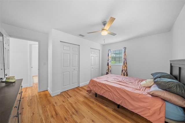 bedroom featuring light hardwood / wood-style floors, two closets, and ceiling fan