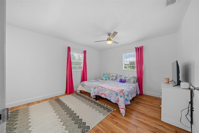 bedroom with hardwood / wood-style flooring, multiple windows, and ceiling fan