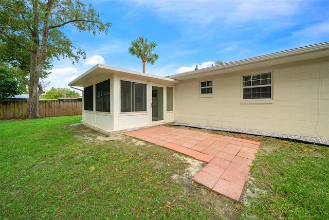 rear view of house with a yard, a patio area, and a sunroom