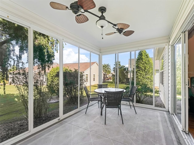 sunroom with outdoor dining space, ceiling fan, and tile patterned floors