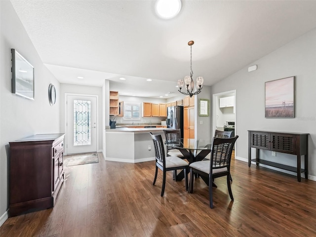 dining space with dark wood-type flooring, vaulted ceiling, and an inviting chandelier