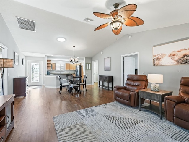 living room with wood-type flooring, ceiling fan with notable chandelier, and vaulted ceiling