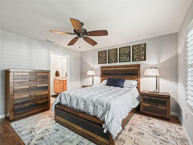 bedroom with ceiling fan, ensuite bath, baseboards, wood finished floors, and visible vents