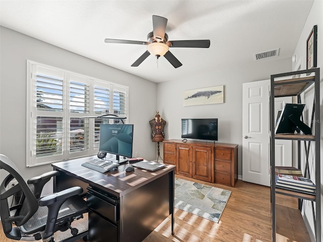 office with light wood-type flooring and ceiling fan