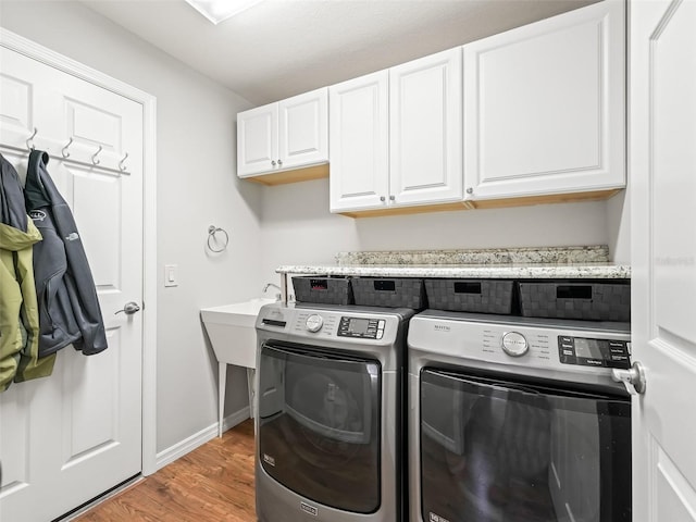 laundry room featuring hardwood / wood-style flooring, washing machine and dryer, and cabinets