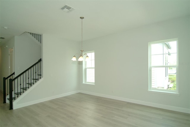 empty room featuring light hardwood / wood-style floors and a chandelier