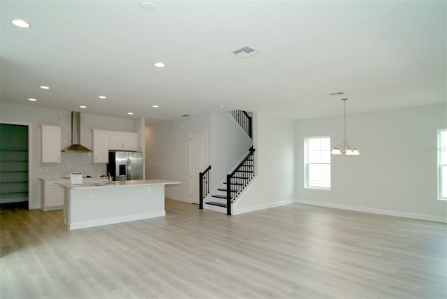 kitchen featuring white cabinetry, wall chimney exhaust hood, light wood-type flooring, and stainless steel refrigerator with ice dispenser