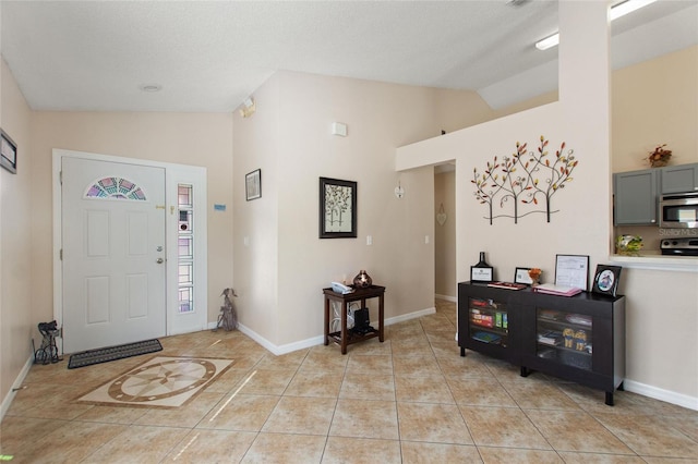 tiled foyer entrance featuring high vaulted ceiling