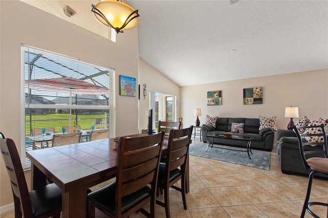 dining room with a textured ceiling, lofted ceiling, and light tile patterned flooring