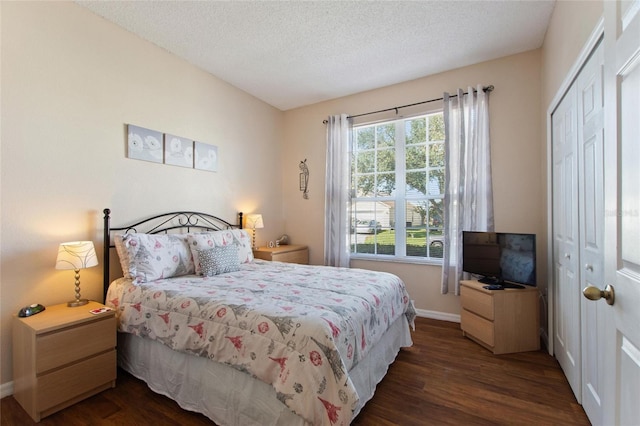 bedroom featuring dark wood-type flooring, a textured ceiling, and a closet