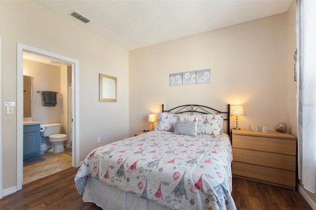 bedroom featuring a textured ceiling, ensuite bathroom, and dark hardwood / wood-style flooring