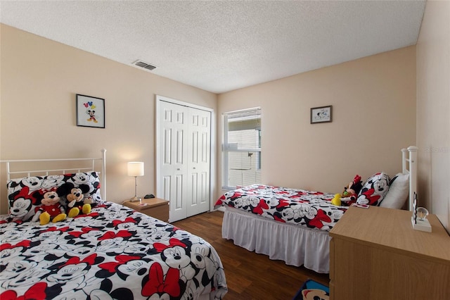 bedroom featuring a closet, a textured ceiling, and dark hardwood / wood-style flooring