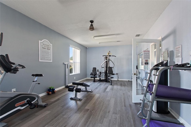 workout area with ceiling fan, a textured ceiling, and hardwood / wood-style floors