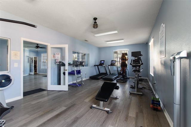 gym featuring french doors, ceiling fan, hardwood / wood-style flooring, and a textured ceiling