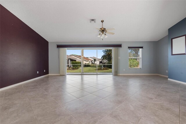 tiled empty room with a healthy amount of sunlight, vaulted ceiling, and ceiling fan