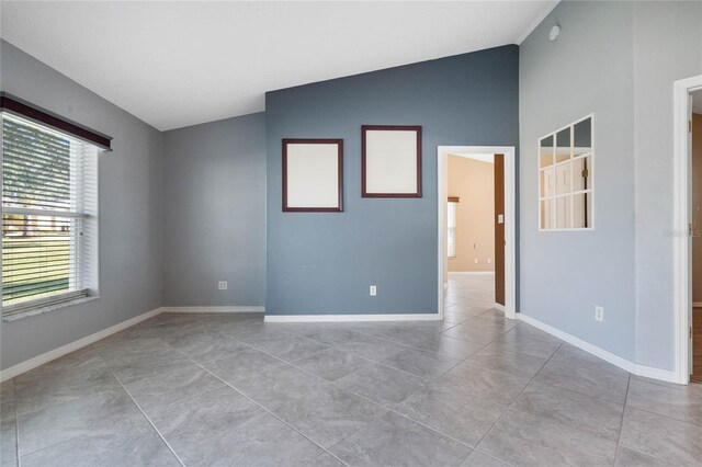 empty room featuring lofted ceiling and light tile patterned flooring