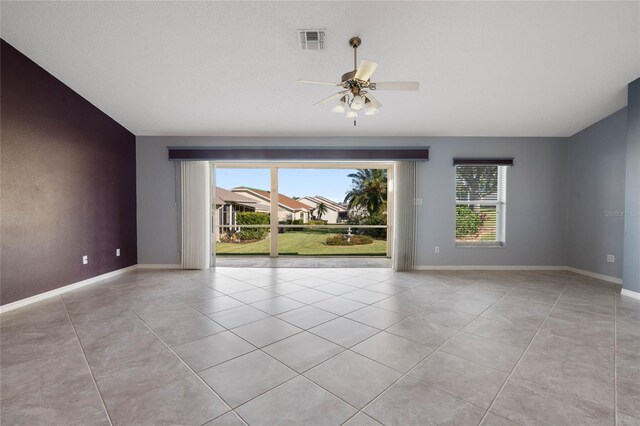 unfurnished room with light tile patterned floors, a healthy amount of sunlight, and ceiling fan