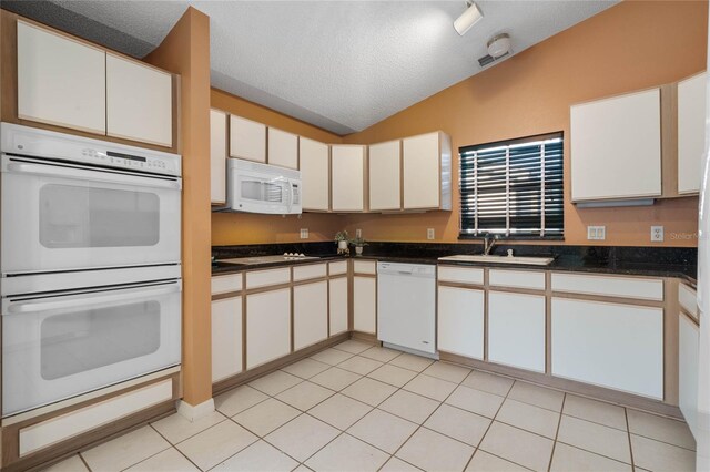 kitchen featuring white appliances, a textured ceiling, white cabinetry, and lofted ceiling