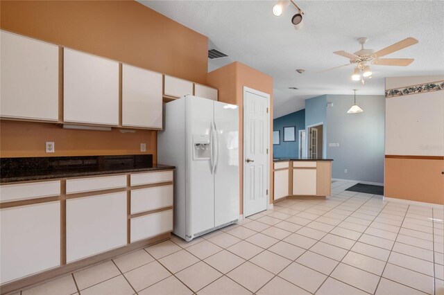 kitchen featuring white fridge with ice dispenser, hanging light fixtures, vaulted ceiling, white cabinets, and ceiling fan