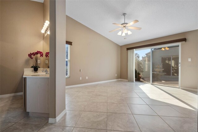 tiled spare room featuring lofted ceiling, sink, a textured ceiling, and ceiling fan