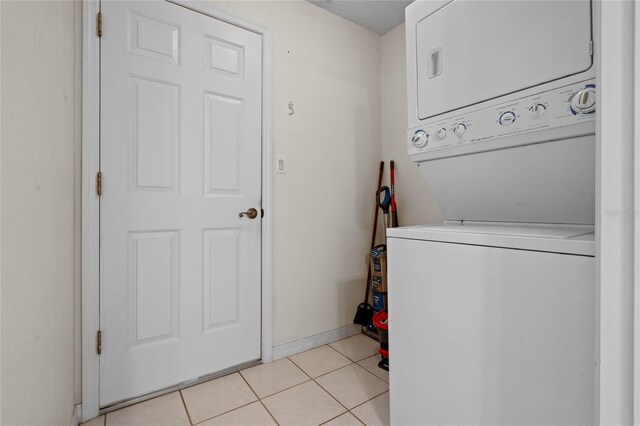 washroom featuring stacked washer / drying machine, a textured ceiling, and light tile patterned floors