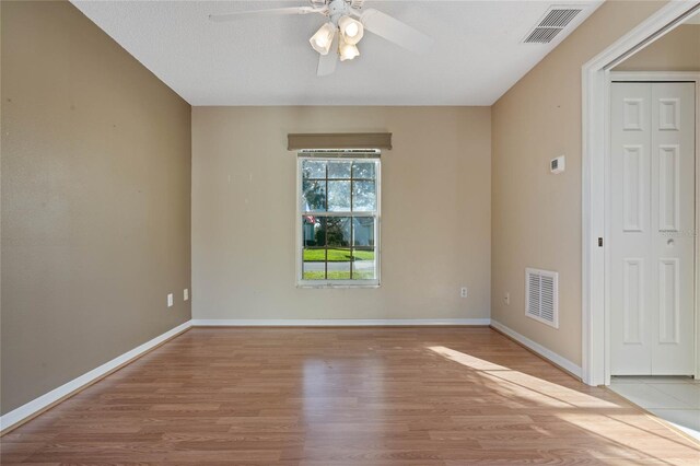 empty room with a textured ceiling, light wood-type flooring, and ceiling fan