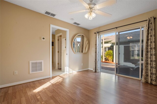 unfurnished room with a textured ceiling, light wood-type flooring, and ceiling fan