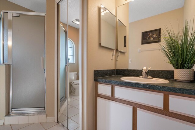 bathroom featuring a shower with door, a textured ceiling, toilet, tile patterned floors, and vanity