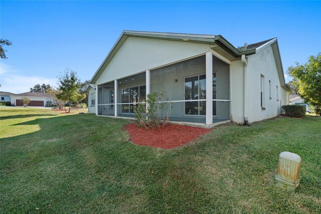 back of house featuring a lawn and a sunroom