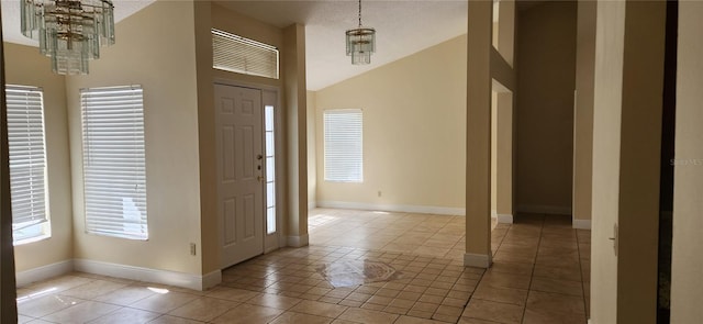 entryway featuring a textured ceiling, light tile patterned floors, lofted ceiling, and a chandelier