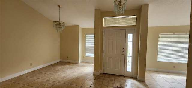 foyer entrance featuring high vaulted ceiling, a healthy amount of sunlight, a chandelier, and light tile patterned floors