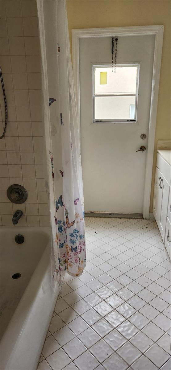 bathroom with shower / bath combo and tile patterned flooring