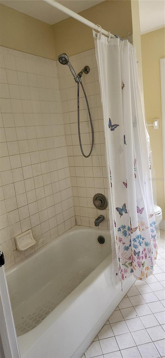 bathroom with shower / bath combo with shower curtain, tile patterned floors, and toilet