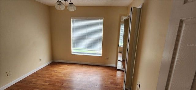 spare room with light wood-type flooring, a chandelier, and plenty of natural light