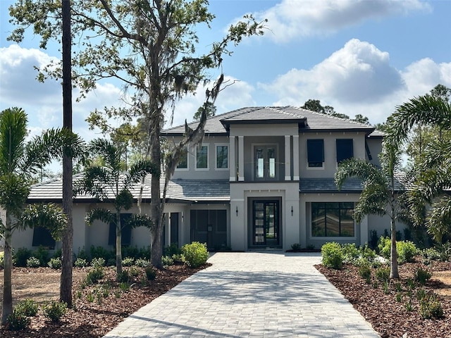 view of front of house with decorative driveway, french doors, and stucco siding