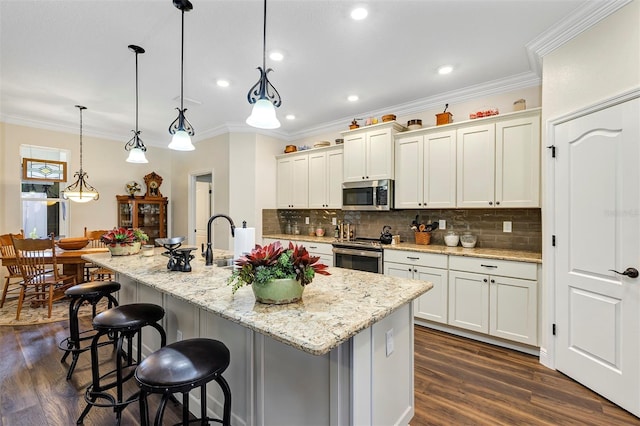 kitchen featuring stainless steel appliances, hanging light fixtures, dark hardwood / wood-style floors, and a kitchen island with sink