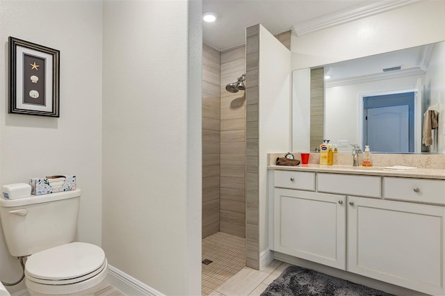 bathroom with toilet, ornamental molding, vanity, and tiled shower