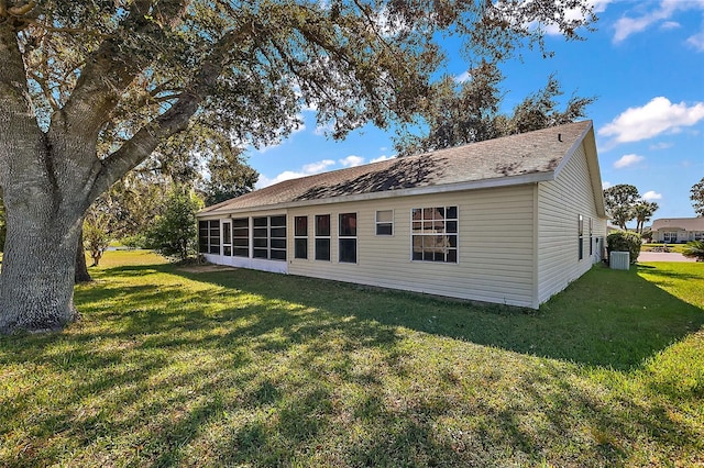 back of property featuring cooling unit, a sunroom, and a lawn