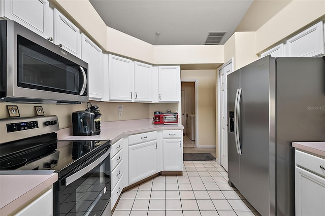 kitchen featuring light tile patterned flooring, white cabinets, and stainless steel appliances